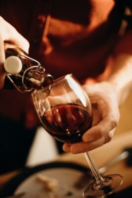 person pouring wine on wine glass